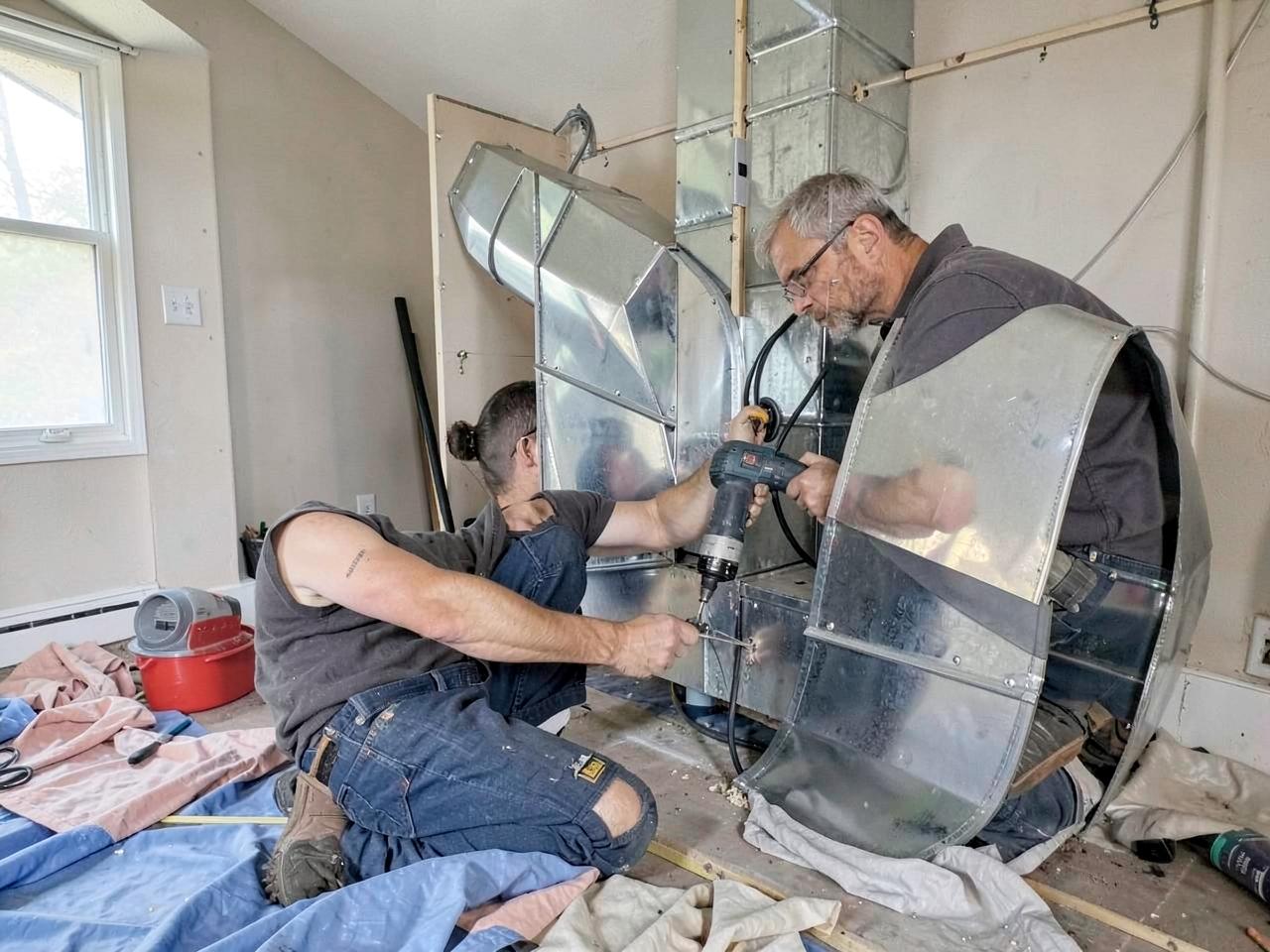 Installers setting a new high-efficiency gas furnace in a basement